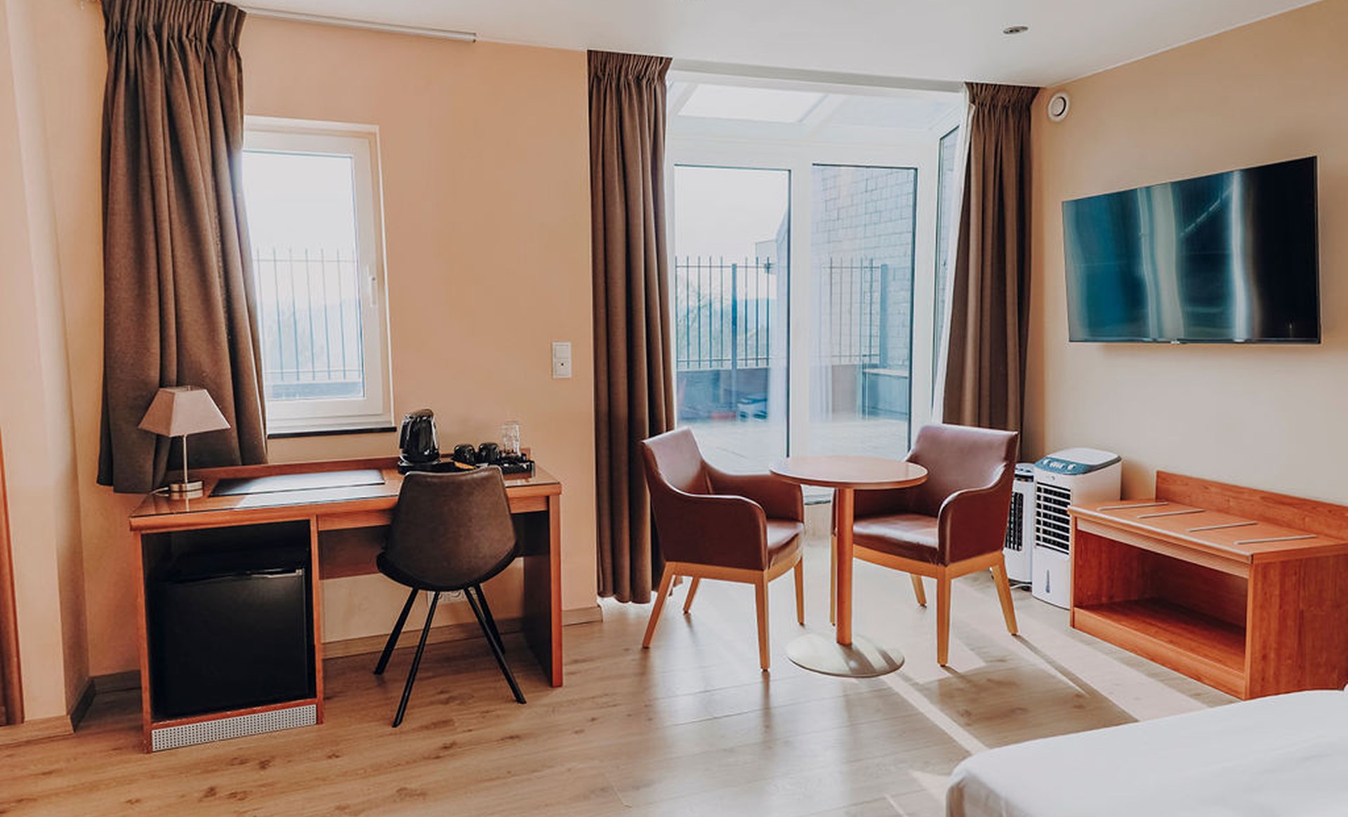 Junior suite avec coin bureau, table, fauteuils et télévision murale, Maison Melba