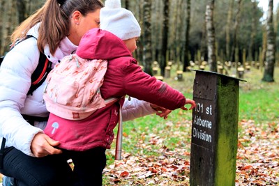 Mère et enfant lisant une plaque au Bois de la Paix à Bastogne