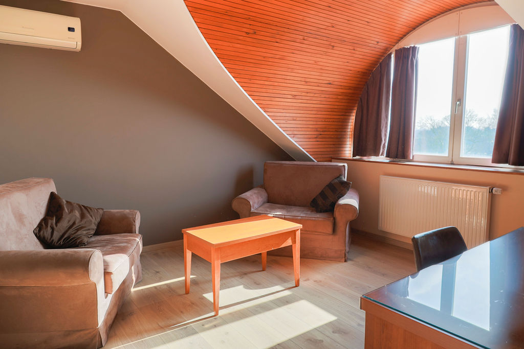 Salon mansardé avec fauteuils et table basse dans une suite de Maison Melba