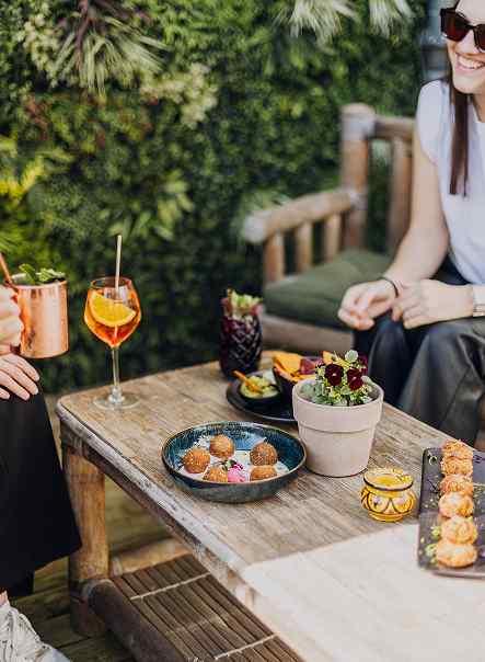 Table garnie de plats et bougies devant le mur végétal du Mel'ting Pot