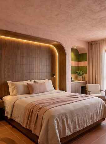 Lit double avec tête de lit arrondie et éclairage indirect dans une chambre de Maison Melba