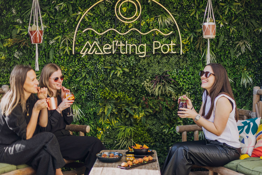 Amies trinquant devant le mur végétal du restaurant Mel'ting Pot à Bastogne