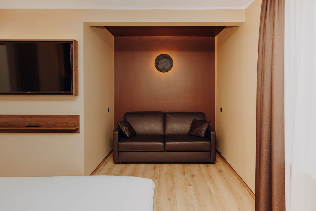Coin salon avec canapé en cuir et télévision dans une suite de Maison Melba