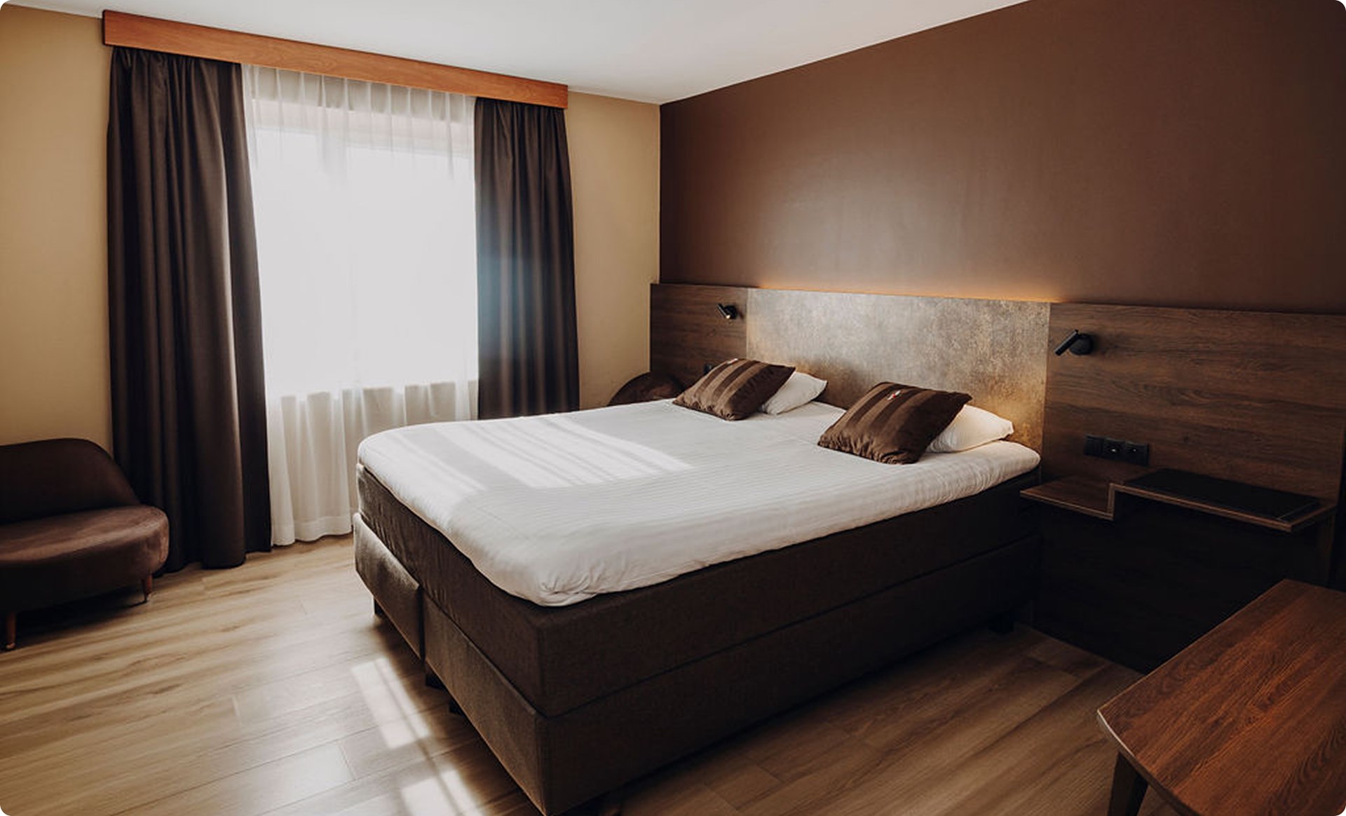 Chambre exécutive aux tons bruns avec grands rideaux, Maison Melba Bastogne