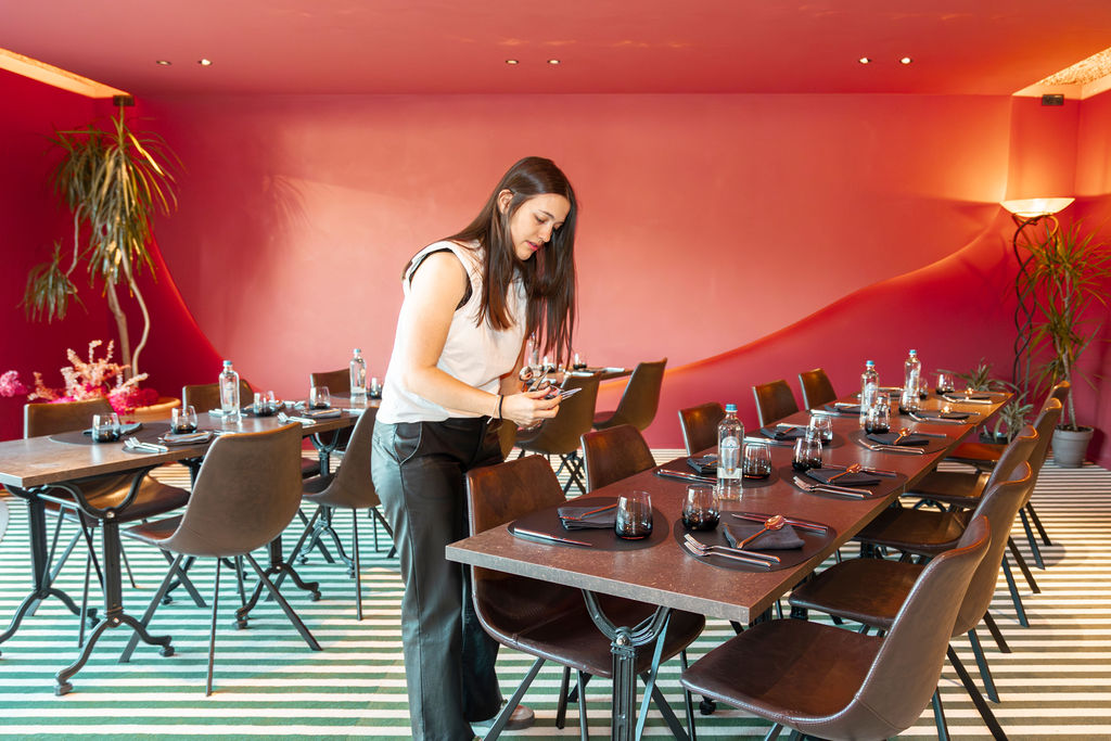 Serveuse dressant les tables de la salle rouge du Mel'ting Pot, restaurant à Bastogne